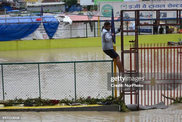 Nepalese man crossing iron fence as water overflowed from River affected due to incessant rainfall at Thimi, Bhaktapur, Nepal on Thursday, July 12,...