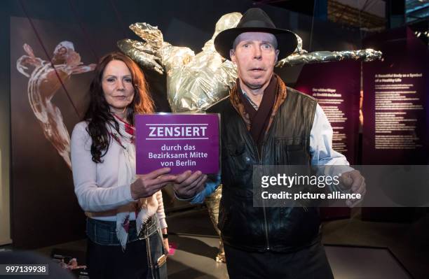 Plastinator Gunther von Hagens and his wife, curator Angelina Whalley, standing in front of a gold-plated plastinated figure in the Menschen Museum...