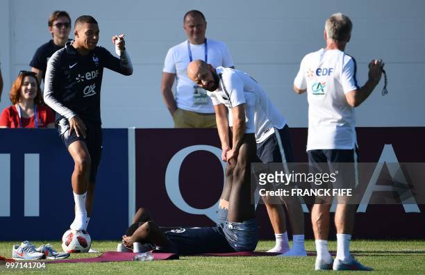 France's forward Kylian Mbappe speaks with France's head coach Didier Deschamps during a training session at the Glebovets stadium in Istra, some 70...
