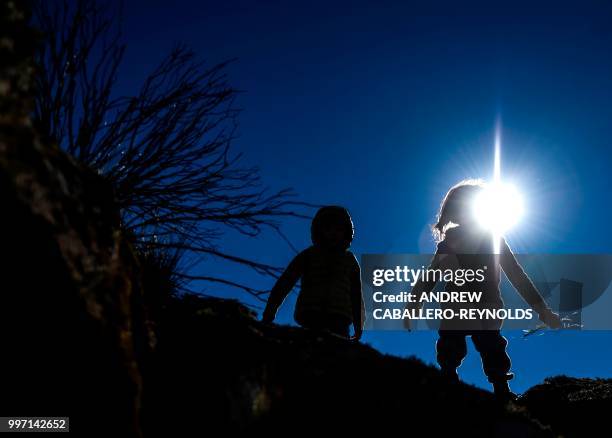 Two children walk on rocks in the remote mountain region of the Pampa de Achala in Cordoba province on July 7, 2018. - The Pampa de Achala is a vast...