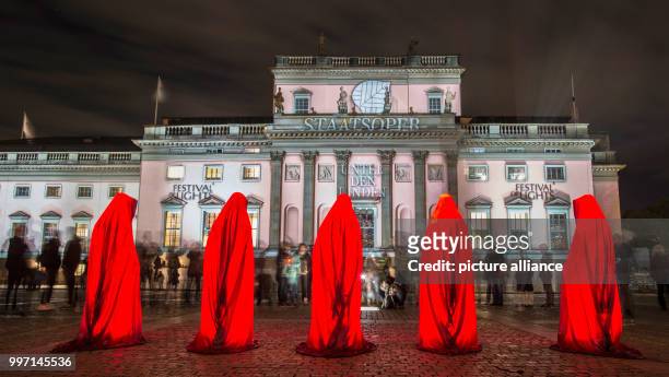 The 'Guardians of Time' stone statues, cloaked in hooded robes, are seen outside the Staatsoper Unter den Linden during the Festival of Lights in...