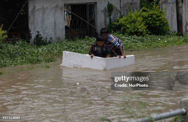 People cross the flooded street caused by swollen Hanumante River following by heavy rainfall at Thimi, Bhaktapur on the outskirts of Kathmandu,...