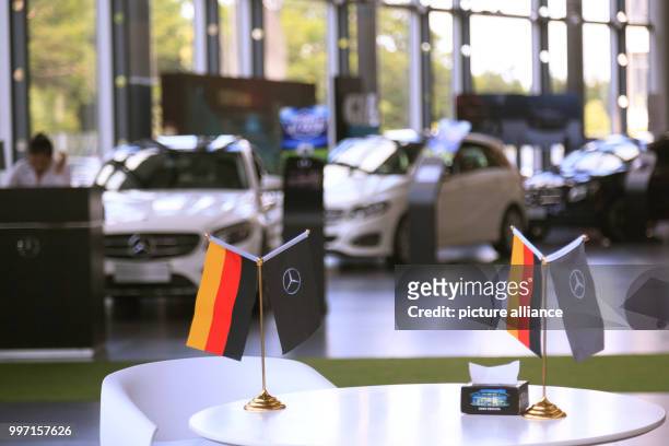 July 2018, China, Guangzhou: German flags in a Mercedes-Benz car showroom in Guangzhou. Mercedes leads the auto mobile market specially due to the...