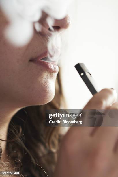 Person smokes a Juul Labs Inc. E-cigarette in this arranged photograph taken in the Brooklyn Borough of New York, U.S., on Sunday July 8, 2018. Juul...