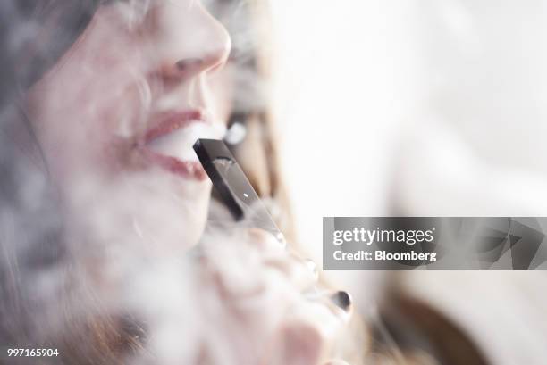 Person smokes a Juul Labs Inc. E-cigarette in this arranged photograph taken in the Brooklyn Borough of New York, U.S., on Sunday July 8, 2018. Juul...