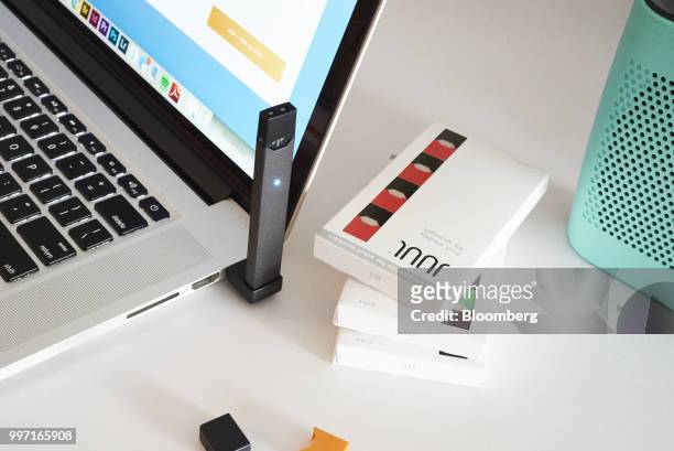 Juul Labs Inc. E-cigarette is charged on a laptop computer next to flavored pods in this arranged photograph taken in the Brooklyn Borough of New...