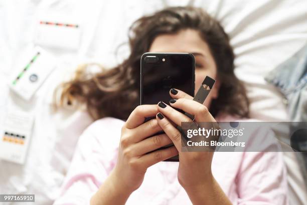 Person views a mobile device while holding a Juul Labs Inc. E-cigarette in this arranged photograph taken in the Brooklyn Borough of New York, U.S.,...