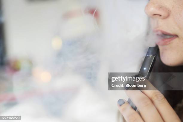 Person smokes a Juul Labs Inc. E-cigarette in this arranged photograph taken in the Brooklyn Borough of New York, U.S., on Sunday July 8, 2018. Juul...