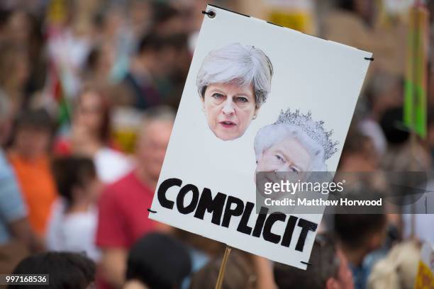 Protester holds a sign showing the face of the Prime Minister Theresa May and the Queen during a protest on the Hayes in Cardiff against a visit by...