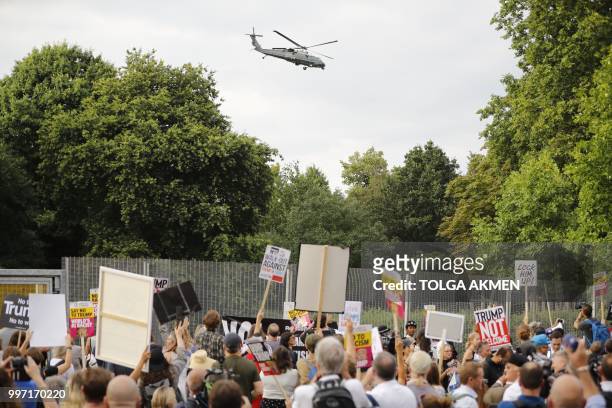 Protesters gathered at the security fence watch as US President Donald Trump and US First Lady Melania Trump leave in Marine One from the US...
