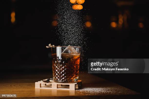 dusting whiskey drink with  ice  on  wood in bar - cognac glass stock-fotos und bilder