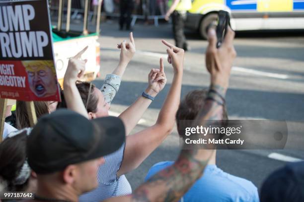 Protesters extend their middle fingers towards the gates of Blenheim Palace where U.S. President Donald Trump is due at a evening function in...