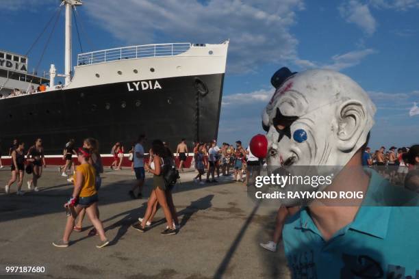 People walk past a boat during the Electro Beach festival in Barcares, southern France on July 12, 2018.