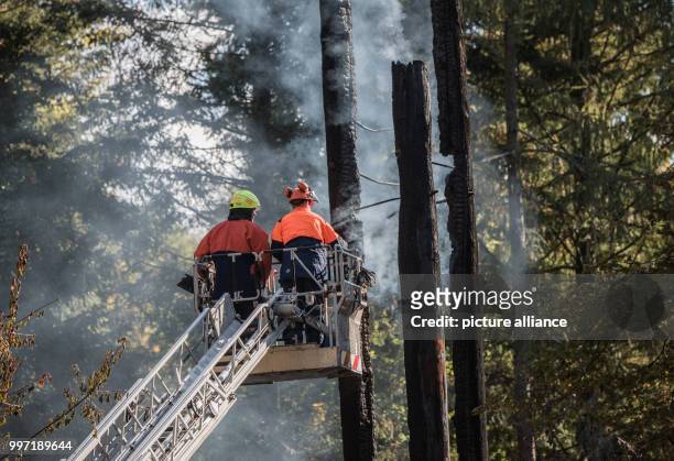 Two firefighters standing on an aerial ladder in front of the smoking remains of the Goether Tower in Frankfurt am Main, Germany, 12 October 2017....