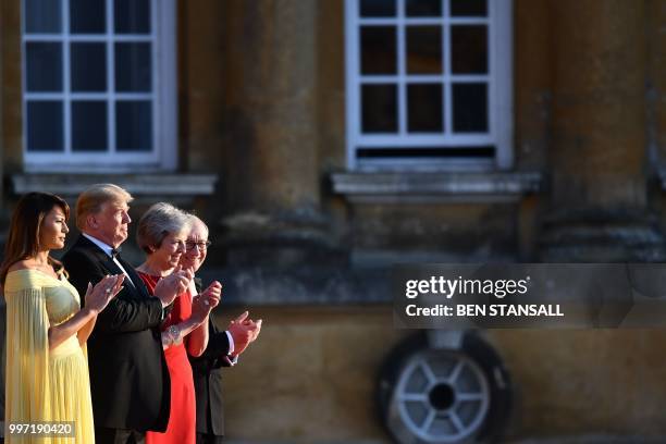 First Lady Melania Trump, US President Donald Trump, Britain's Prime Minister Theresa May and her husband Philip May applaud on steps in the Great...