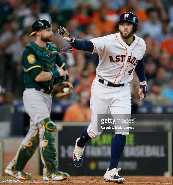George Springer of the Houston Astros walks in the third inning as Jonathan Lucroy of the Oakland Athletics looks on at Minute Maid Park on July 12,...