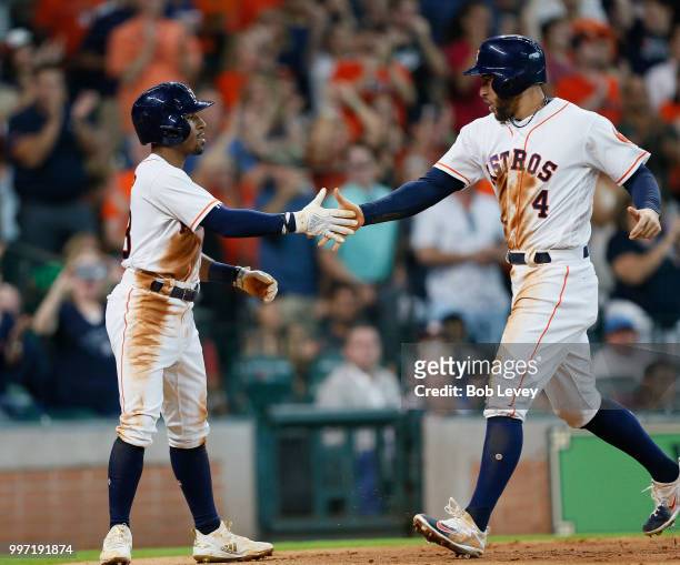Tony Kemp of the Houston Astros shakes hands with George Springer after they scored on Alex Bregman double in the third inning against the Oakland...