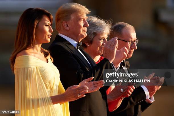 First Lady Melania Trump, US President Donald Trump, Britain's Prime Minister Theresa May, and her husband Philip May stand on the steps in the Great...