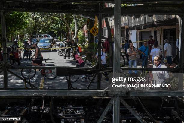 People look at a bus set on fire by gang members near Comuna 13 neighbourhood in Medellin, Antioquia Department, Colombia, on July 12, 2018. -...