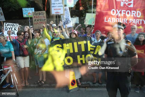 Protesters seen from a coach window hold up placards along the route at Blenheim Palace prior the arrival of U.S. President Donald Trump and First...