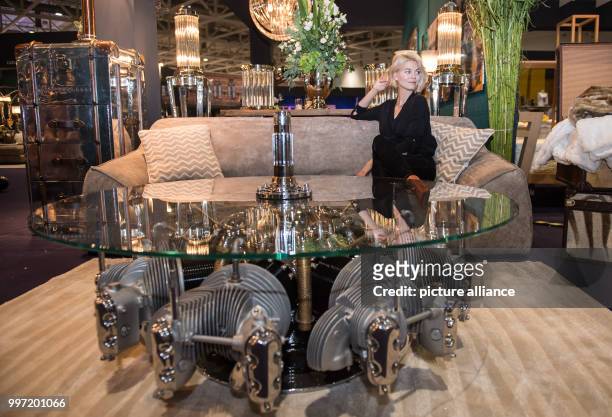 Model Louisa sits next to a table from 1936 made our of an aircraft engine and a glass plate during a pre-tour of the event and sales trade show...