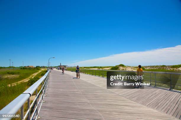 people riding and running on boardwalk, jones beach, ny - barry wood stock-fotos und bilder