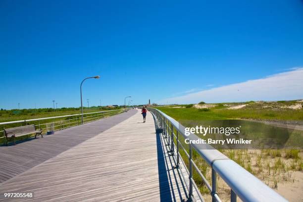 woman jogging on boardwalk, jones beach, ny - barry wood stock-fotos und bilder