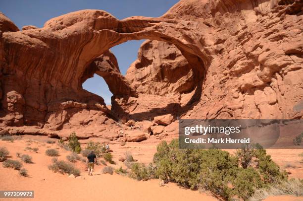 tourists at double arch in arches np - double arch foto e immagini stock