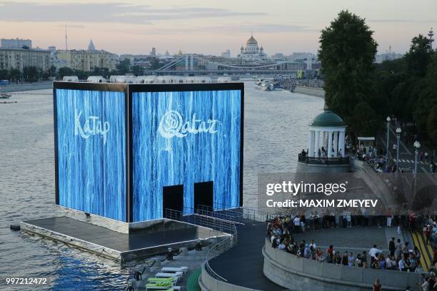 People look at the illuminated walls of Majlis Qatar pavilion light in Moscow's Gorky Park in Moscow on July 12, 2018. - Qatar will host of the FIFA...