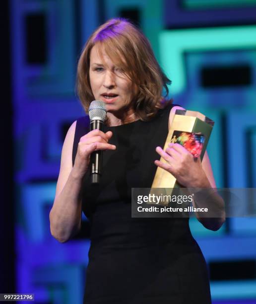 Actress Corinna Harfouch delivers her acceptance speech while holding her award trophy in her hand during the award ceremony of the 'Hessische Film-...