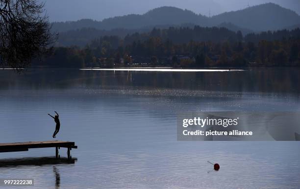 Young woman jumps into the air from a jetty enjoying the Autumn weather at Lake Forggensee in Buching, near Schwangau, Germany, 13 October 2017....