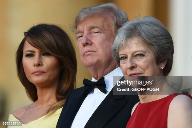 First Lady Melania Trump, US President Donald Trump and Britain's Prime Minister Theresa May stand on steps in the Great Court as the bands of the...