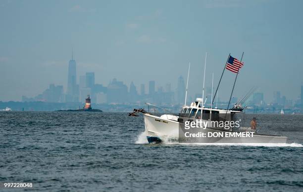 Fishing boats make their way through the waters off Sandy Hook with Manhattan in the background July 12, 2018 near Middletown, New Jersey.