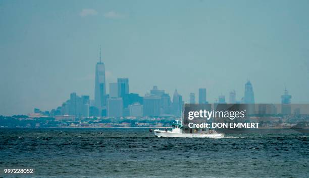 Fishing boats make their way through the waters off Sandy Hook with Manhattan in the background July 12, 2018 near Middletown, New Jersey.