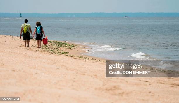 Couple walks along the beach of Sandy Hook on July 12, 2018 near Middletown, New Jersey.