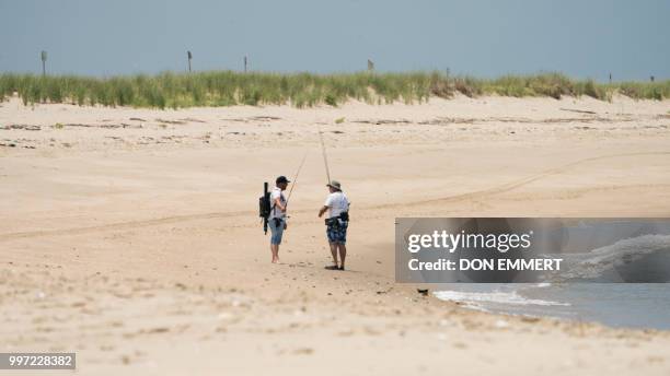 Two fisherman stop to talk as they walk along the beach of Sandy Hook on July 12, 2018 near Middletown, New Jersey.