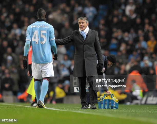 Mario Balotelli of Manchester City listening to manager Roberto Mancini during the Barclays Premier League match between Manchester City and Bolton...