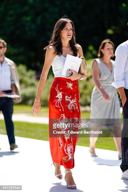 Guest wears a white tank top, a red skirt with embroidered flowers , outside Dior, during Paris Fashion Week Haute Couture Fall Winter 2018/2019, on...
