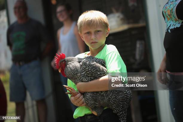 Cash Hawking carries his chicken in to be judged at the Iowa County Fair on July 12, 2018 in Marengo, Iowa. The fair, like many in counties...
