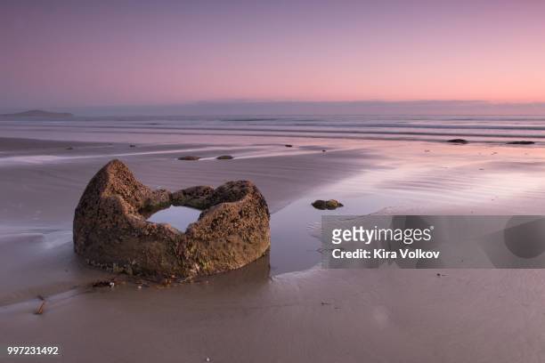fraction of a boulder on the ocean shore at sunrise - moeraki boulders stock pictures, royalty-free photos & images
