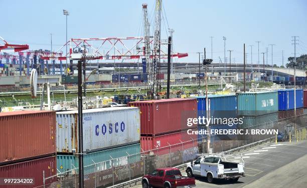 Shipping containers, including those from COSCO, a Chinese state-owned shipping and logistics company await transportation on a rail line at the Port...