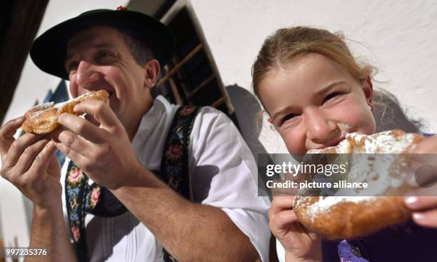 Sofia and her father Reiner biting into so-called Kirta noodles at the traditional church consecration festival in the outdoor museum of Glentleiten,...