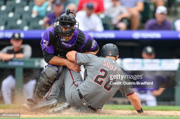 Chris Iannetta of the Colorado Rockies applies a tag and holds on to the ball as Steven Souza Jr. #28 of the Arizona Diamondbacks collides with him...