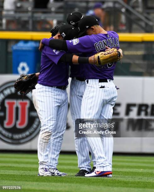 Colorado Rockies left fielder Gerardo Parra, and teammates Charlie Blackmon, center, and Carlos Gonzalez hug it out at the end of the game against...