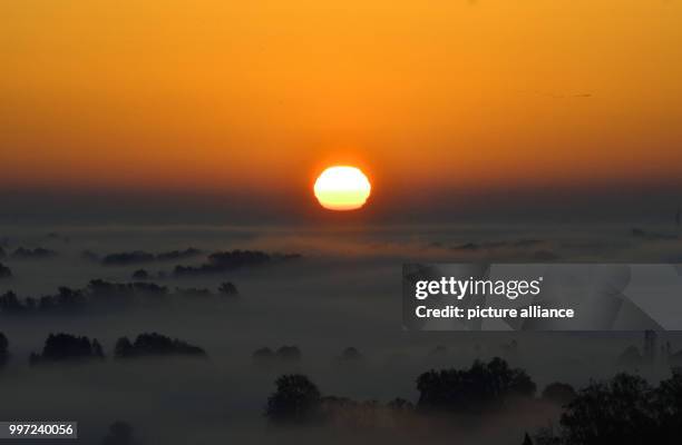 The sun rises over a foggy valley in Niederfinow, Germany, 16 October 2017. Photo: Paul Zinken/dpa