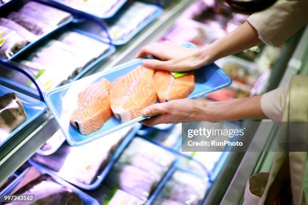 woman holding tray of fresh salmon in supermarket - viswinkel stockfoto's en -beelden