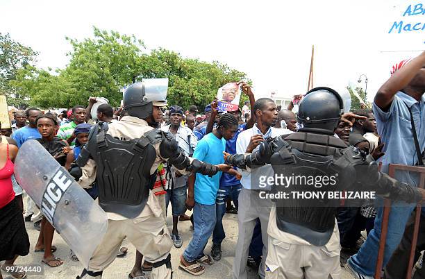 Haitians march past riot police as they demonstrate near the presidential palace in Port-au-Prince on May 17, 2010 against President Rene Preval's...