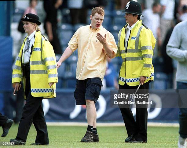 Police lead fans off as they run on the pitch at the end of the match between Queens Park Rangers and Chelsea in a pre-season friendly at Loftus...