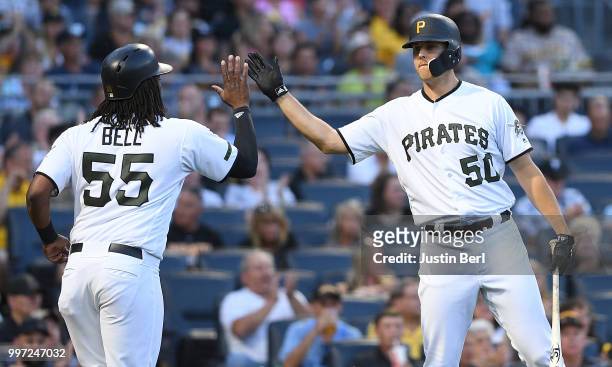Josh Bell of the Pittsburgh Pirates high fives with Jameson Taillon after coming around to score on an RBI single by Jordy Mercer in the fourth...