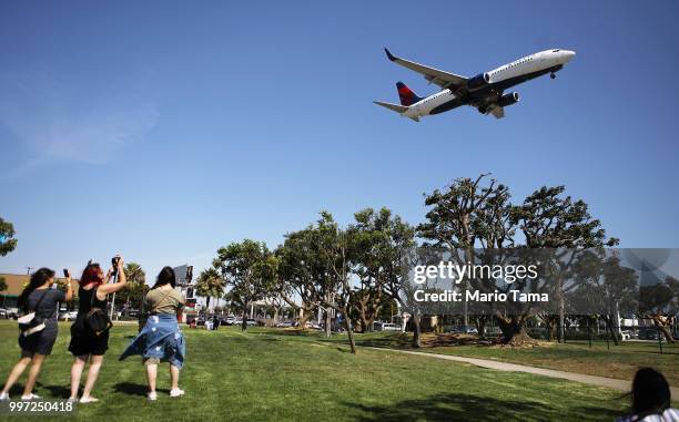 People take photos as a Delta Air Lines plane lands at Los Angeles International Airport on July 12, 2018 in Los Angeles, California. Delta announced...